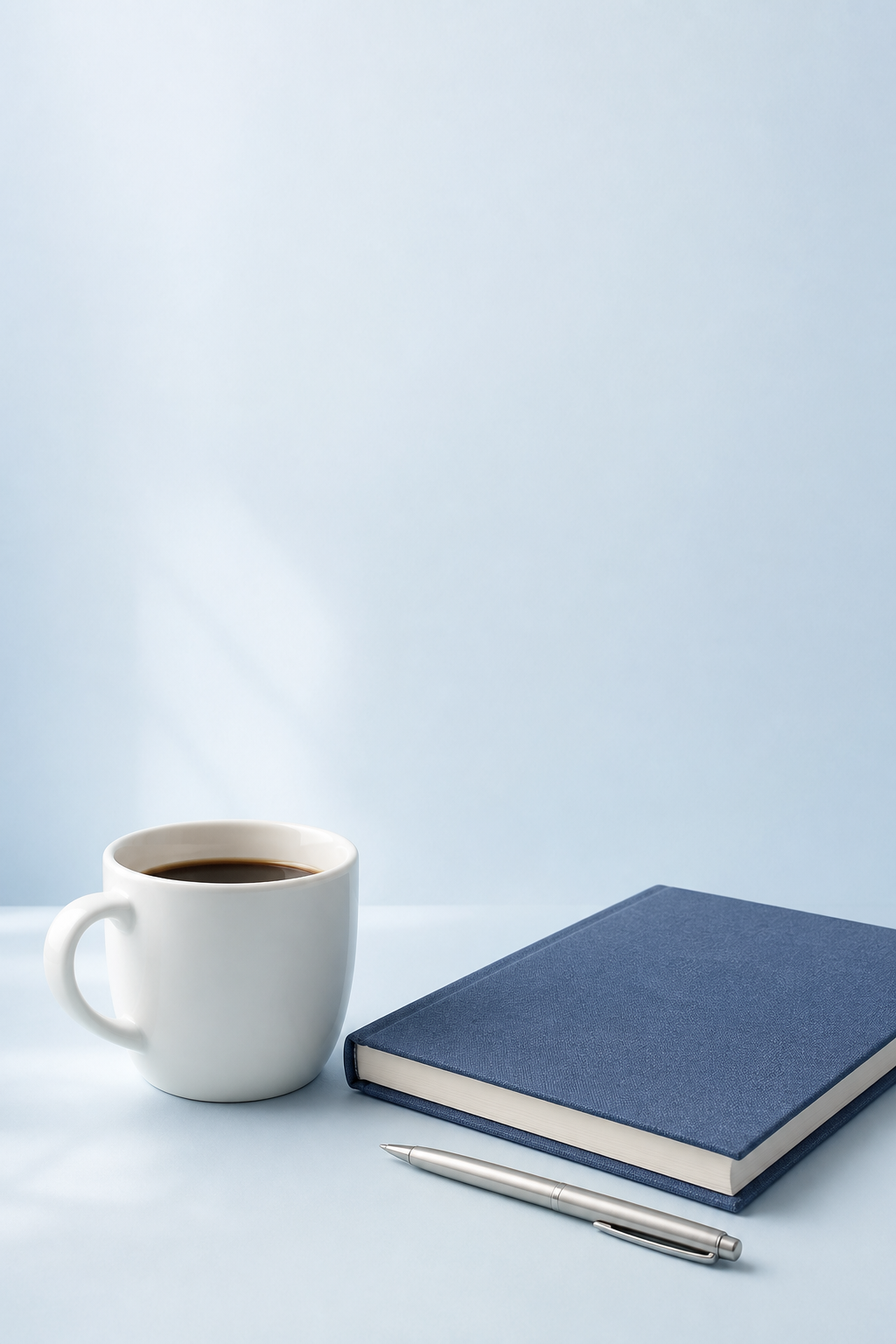 Coffee, a blue notebook, and a pen arranged for pre-call preparation